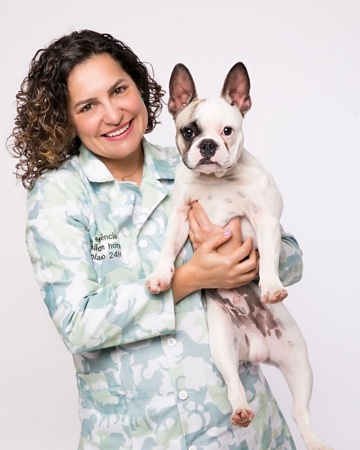 Karine Pacheco sorrindo com um buldogue francês no colo